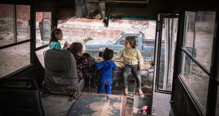 Niños y niñas jugando en un autobús en Siria