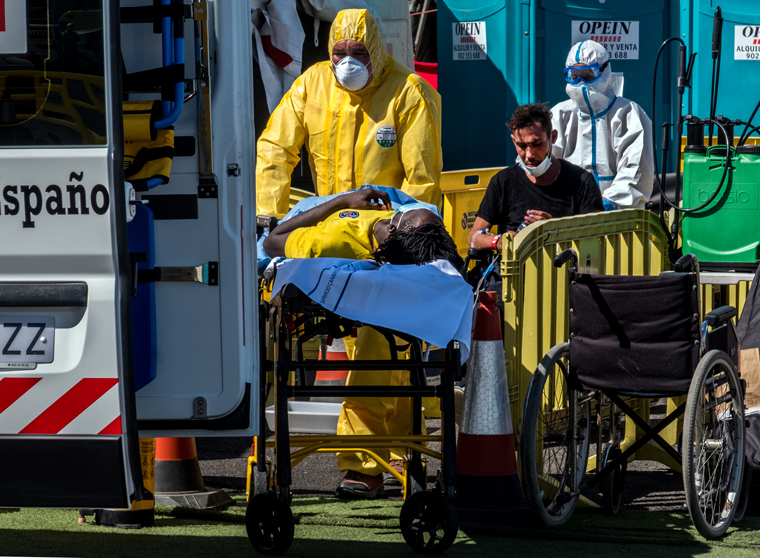 Sanitarios evacuan al hospital a dos personas migrantes tras desembarco en el muelle de Arguineguín, después de ser rescatados por Salvamento Marítimo. Fotografía: Javier Bauluz.