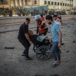 Un grupo de personas intentan evacuar a un anciano incapacitado de la zona que fue bombardeada en la Franja de Gaza.