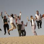 Voluntariado de Médicos del Mundo saltando de alegría en una duna del desierto del Sáhara