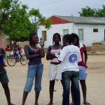 Una educadora de Médicos del Mundo habla sobre el VIH con cuatro mujeres jóvenes en el Día Mundial de la lucha contra el Sida, en una calle de Loungo, Angola.