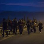 Personas refugiadas caminan de noche por una carretera europea