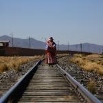 Una mujer boliviana vestida con prendas típicas camina por la vías del tren a su paso por el pueblo de Patacamaya